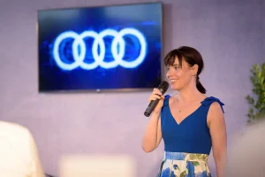 Audi A6 bemutató rendezvény megnyitó beszéde, a háttérben az Audi logoval.
