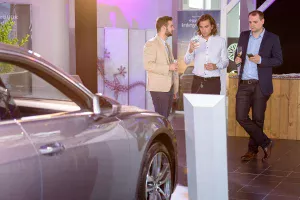 Audi A6 bemutató oldalról az autó, a háttérben az autó elejénél a vendégek.