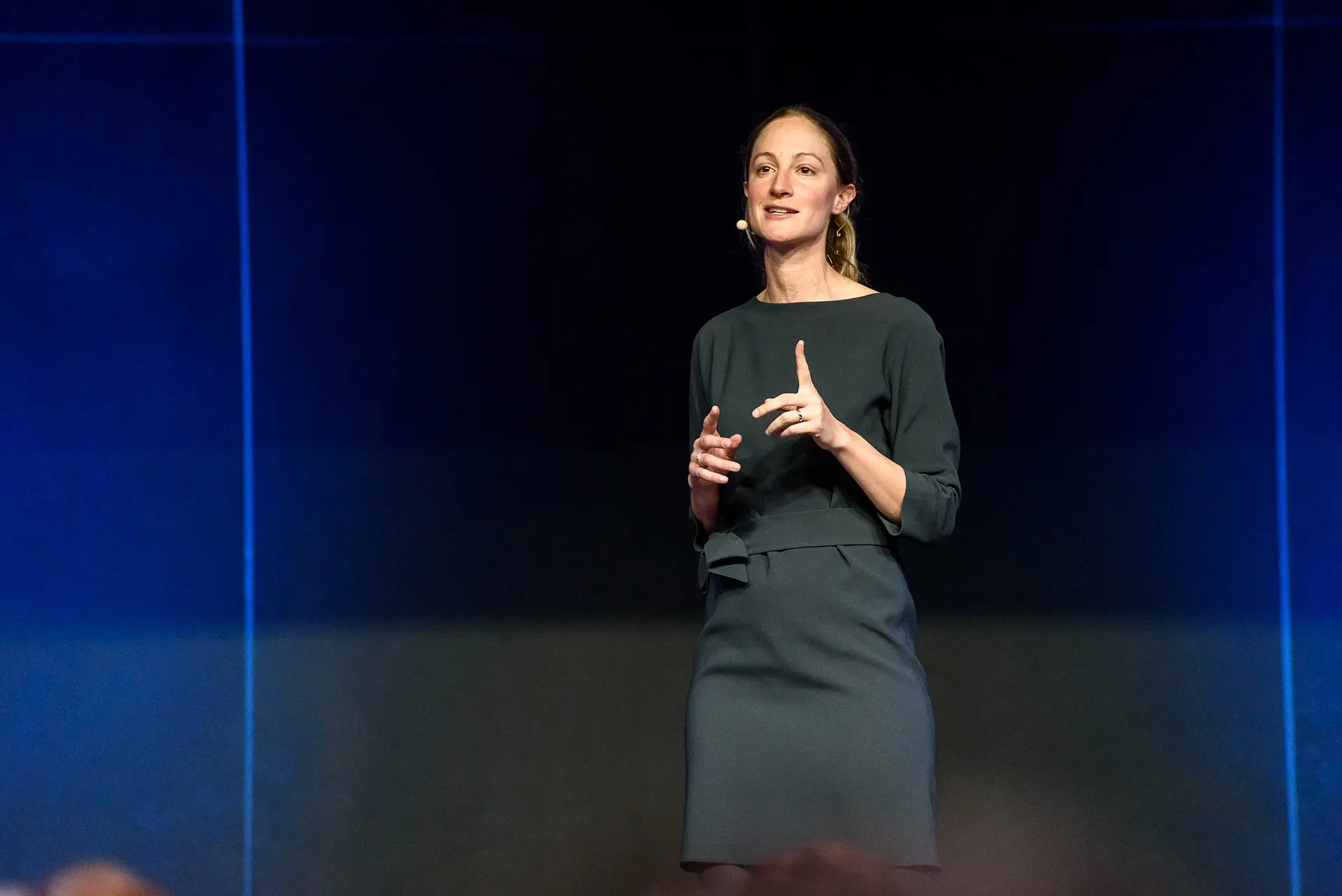 Konferencia fotózás Budapest egy nő beszédet tart a színpadon, felemelt mutatóujjal.